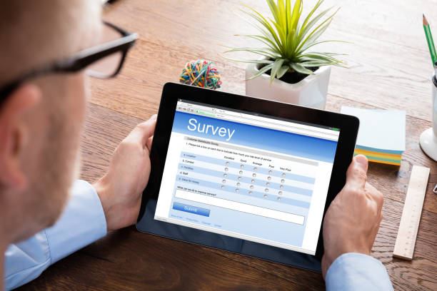Person Filling Online Survey Form On Digital Tablet At Wooden Desk